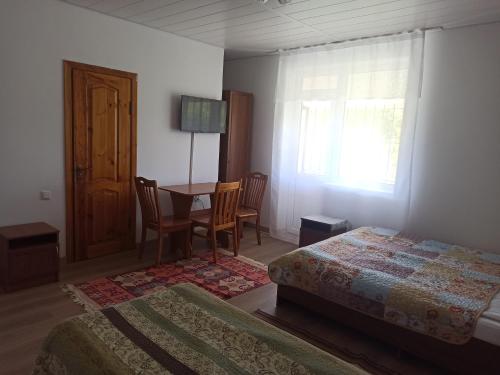 1 dormitorio con 2 camas, mesa y ventana en Meerim Murok en Bosteri