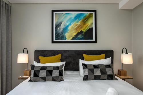 a bedroom with a bed with two lamps and a painting at The Regency Apartments in Pretoria