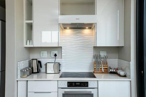 a kitchen with white cabinets and a stove top oven at The Regency Apartments in Pretoria