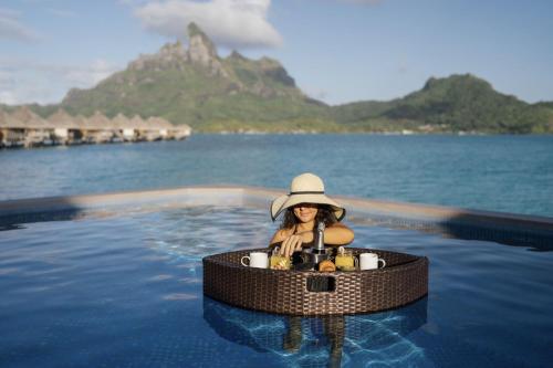 a woman in a swimming pool in the water at The St. Regis Bora Bora Resort in Bora Bora