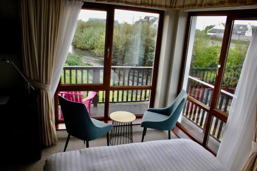 a hotel room with a balcony with a bed and chairs at Riverbank Rooms in Doolin