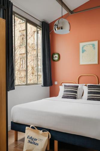 Ce lit se trouve dans un dortoir doté de murs orange et d'une fenêtre. dans l'établissement Edgar Suites Martyrs - Loft, à Paris