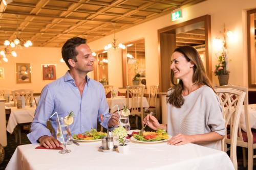 un hombre y una mujer sentados en una mesa comiendo comida en OptimaMed Gesundheitsresort Weißbriach GmbH, en Weissbriach