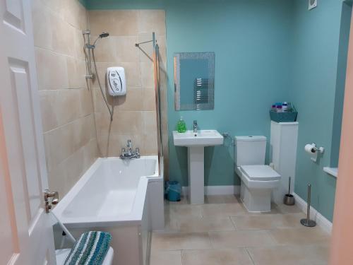 a bathroom with a tub and a sink and a toilet at Blackpool Abode - Caxton Lodge in Blackpool