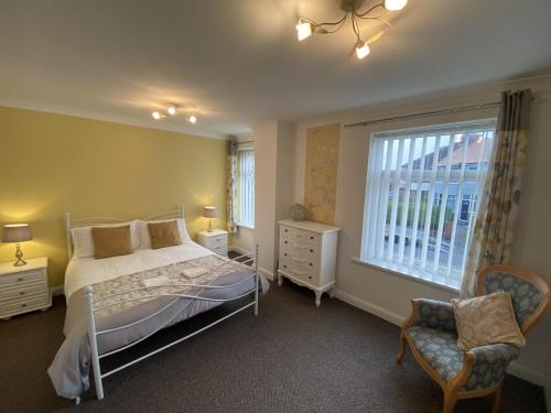 a bedroom with a bed and a window and a chair at Blackpool Abode - Caxton Lodge in Blackpool