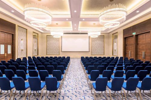 a conference room with chairs and a screen at Al Messila, A Luxury Collection Resort & Spa, Doha in Doha
