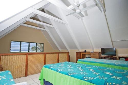 a bedroom with two beds and a tv in it at Whitesands Beach Villas in Rarotonga