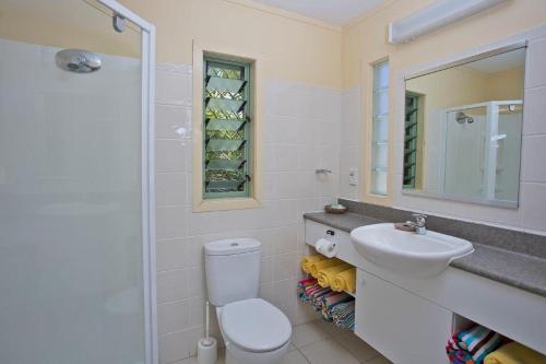 a bathroom with a toilet and a sink and a mirror at Whitesands Beach Villas in Rarotonga