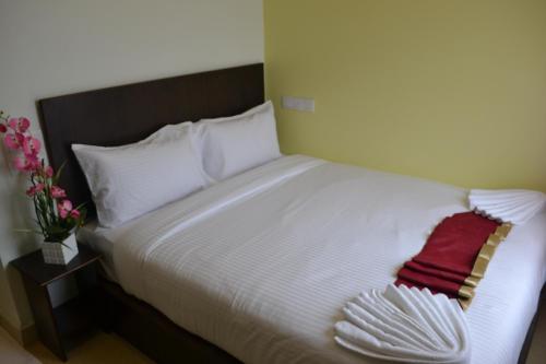 a bed with white sheets and a red towel on it at DR Hotel Penang in Bayan Lepas