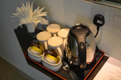 a tea kettle and cups on a table at DR Hotel Penang in Bayan Lepas