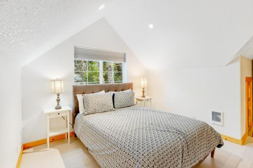 a white bedroom with a bed and two tables at Alder Cove in Tillamook