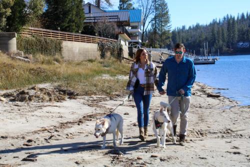 a man and woman walking two dogs on the beach at The Pines Resort & Conference Center in Bass Lake