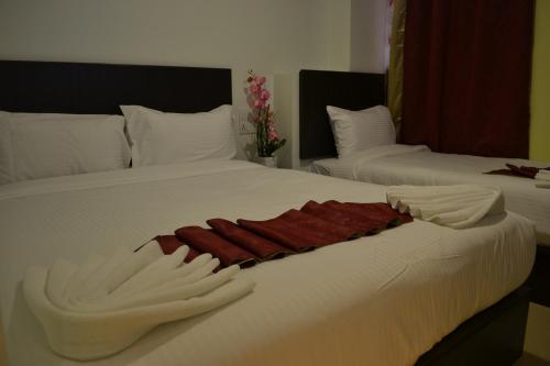 two beds with white sheets and red towels on them at DR Hotel Penang in Bayan Lepas