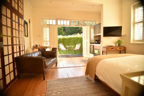 a bedroom with a bed and a couch and a patio at Daisybank Cottage Boutique Bed and Breakfast in Brockenhurst
