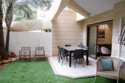 a patio with a table and chairs on the grass at Garden House By IsrApart in Ra‘ananna