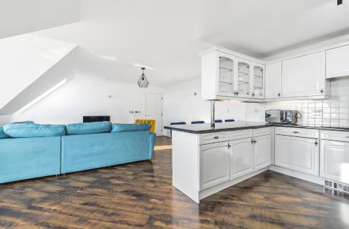 a kitchen and living room with a blue couch at Pochin House Collections in St Austell
