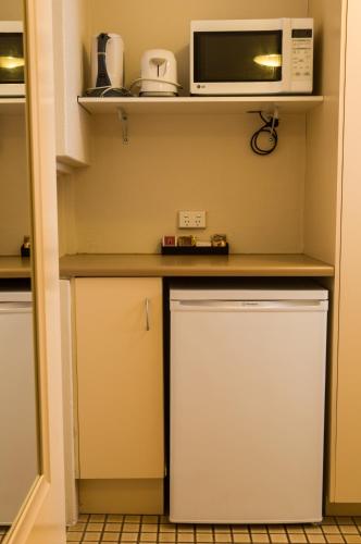 a small kitchen with a microwave and a refrigerator at Lancaster Court Motel in Brisbane