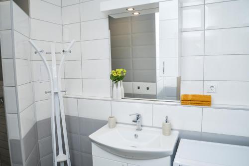 a white bathroom with a sink and a mirror at Flamingó Apartman in Hajdúszoboszló