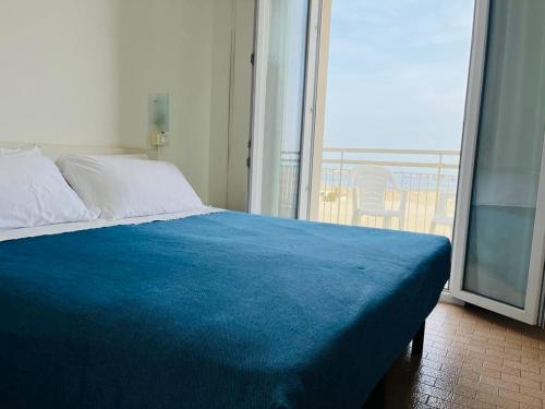 1 cama con manta azul en una habitación con ventana en Hotel Lima, en Lido di Savio