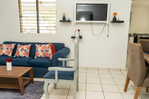 casa acogedora de 3 habitaciones في سانتا باربرا دو سامانا: غرفة معيشة مع أريكة زرقاء وتلفزيون