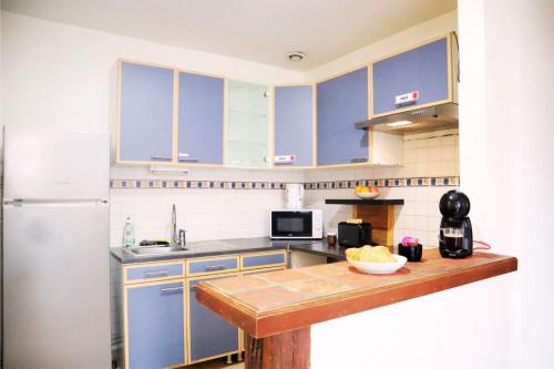 une cuisine avec des placards bleus et un comptoir en bois dans l'établissement Vaillant - Tout confort - Fibre - 5min du Tramway #SirDest, à Bezons