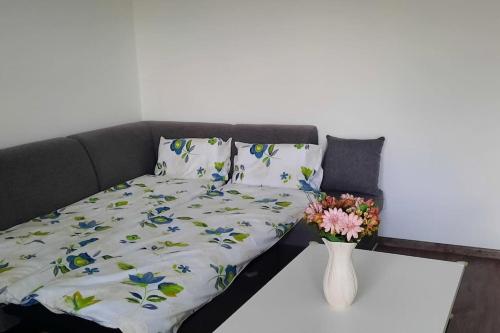 a couch with a blanket and a vase with flowers on it at Apartment Študentská "Free Parking" in Trnava