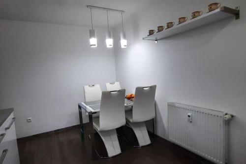 a dining room with a table and two white chairs at Apartment Študentská "Free Parking" in Trnava