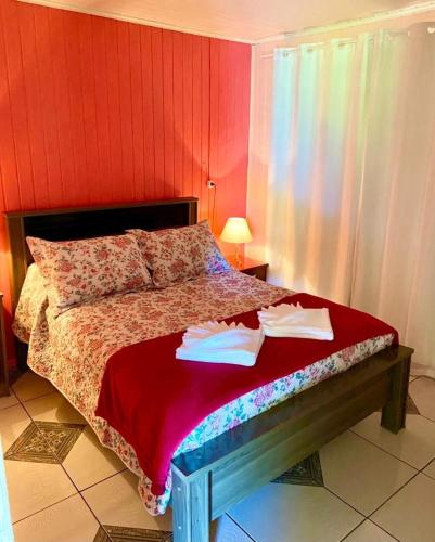 a bedroom with a bed with a red wall at Chalé Recanto dos Pássaros in Gramado