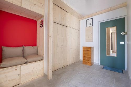 une chambre avec un banc et un mur rouge dans l'établissement Studio a l’aiguille du Midi, à Chamonix-Mont-Blanc