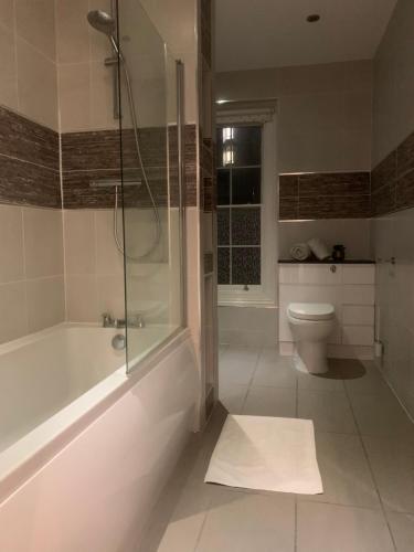 een badkamer met een douche, een bad en een toilet bij HU1 Triplex City Centre Gem sleeps 6 H7 in Hull