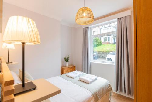 a white bedroom with a bed and a window at The Nook In The Afan Forest Bike Park by StayStaycations in Port Talbot