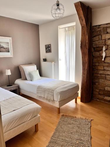 1 dormitorio con 2 camas y pared de ladrillo en Le domaine de Marie en Port-sur-Saône