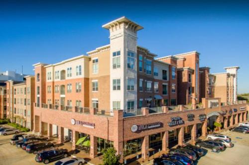 a large building with cars parked in a parking lot at Home felt apartment- Med Center/NRG in Houston