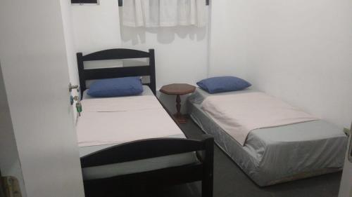 a room with two beds and a table and a door at 4 suítes privativas in Santos