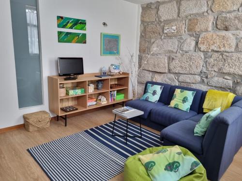 a living room with a blue couch and a stone wall at Honey House in Matosinhos