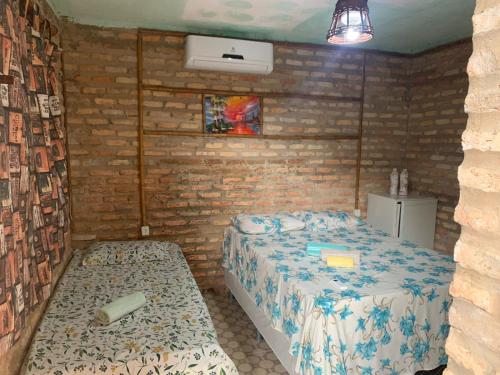 a bedroom with two beds and a brick wall at Villa Sirena Pousada de charme in Beberibe