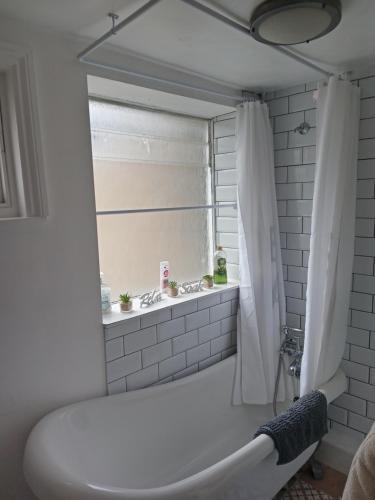 a white bathroom with a tub and a window at Little Dorrit Studio flat Rochester ME1 1XZ in Strood