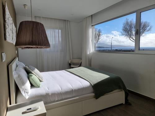 a bedroom with a bed and a large window at Bay House - Seashore Apartment in Ponta Delgada