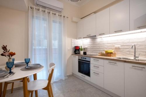 a kitchen with white cabinets and a table and a sink at Helena's Apartment in Corfu town in Corfu Town