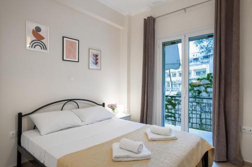 a white bedroom with a bed and a window at Helena's Apartment in Corfu town in Corfu Town