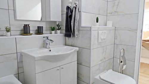 uma casa de banho branca com um lavatório e um WC em Apartment No15 em Koprivnica