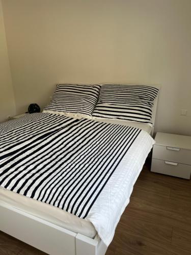 a white bed with black and white sheets and pillows at Ferienwohnungen Fritze Bürger in Schiefling am See