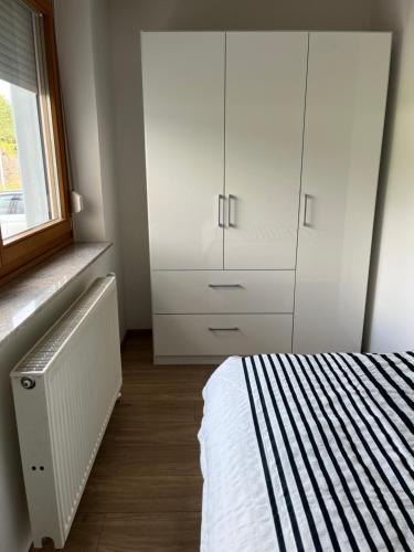 a bedroom with a bed and a white cabinet at Ferienwohnungen Fritze Bürger in Schiefling am See