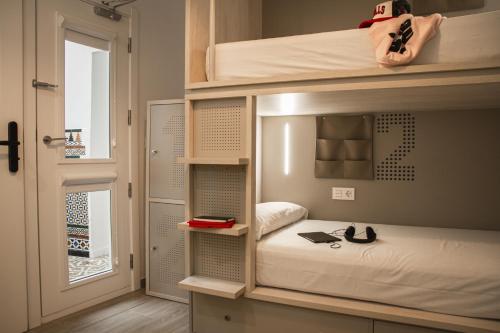 a room with a bunk bed with a laptop on it at room00 Salvador Hostel in Seville