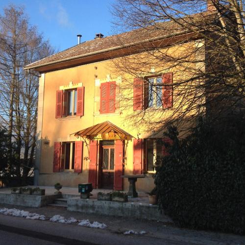 a house with red shuttered windows and a door at Le Fayard in Challonges