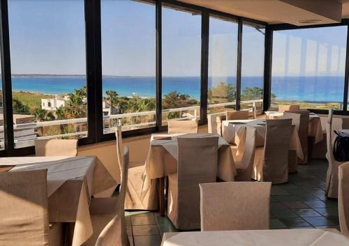un ristorante con tavoli e sedie e vista sull'oceano di Hotel Baia Verde Gallipoli a Gallipoli