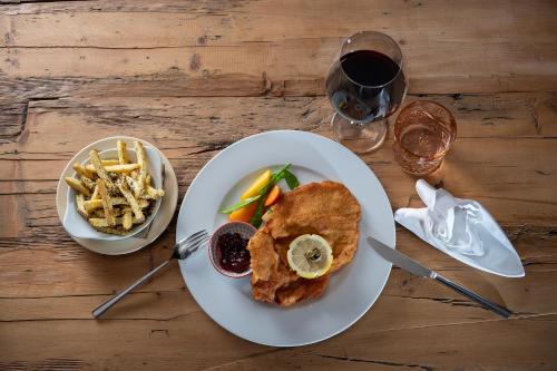 a table with a plate of food and a glass of wine at Hotel Pollux in Zermatt