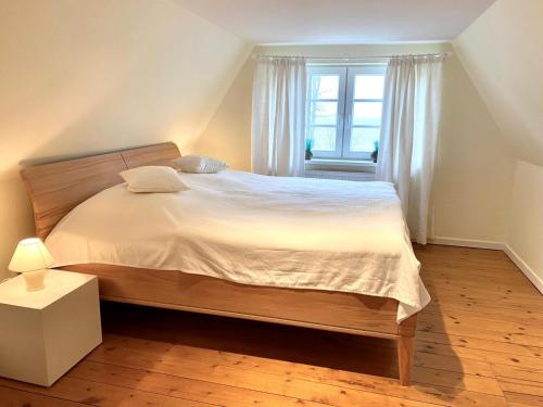 a bedroom with a bed with white sheets and a window at Eichenhof IV in Grothusenkoog