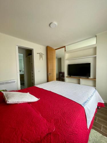 a bedroom with a large bed with a red blanket at Depto a pasos del centro de Puerto Montt in Puerto Montt