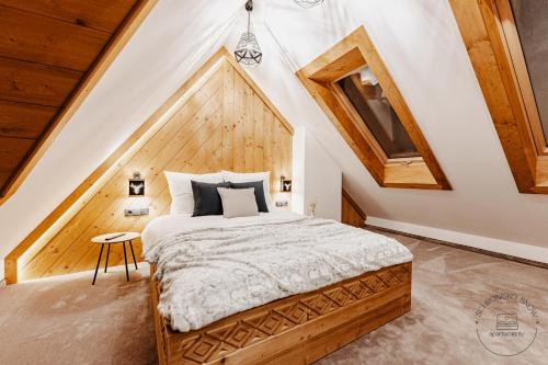 a bedroom with a bed in a room with wooden ceilings at Apartamenty Schronisko Snów in Bukowina Tatrzańska